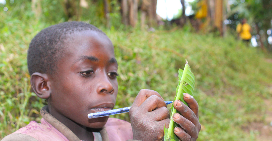child writing in a banana leaf